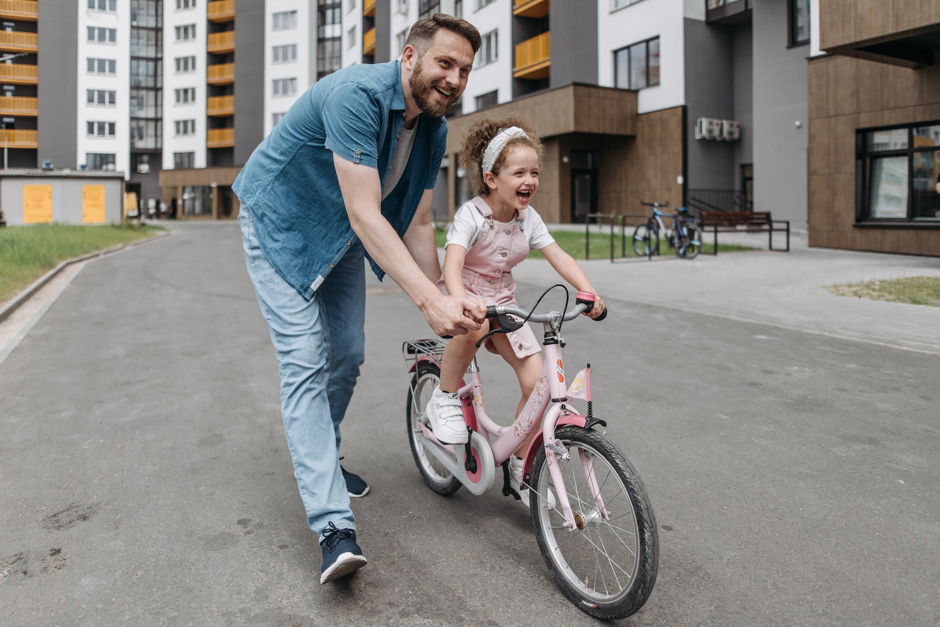 father guiding her daughter riding a bike