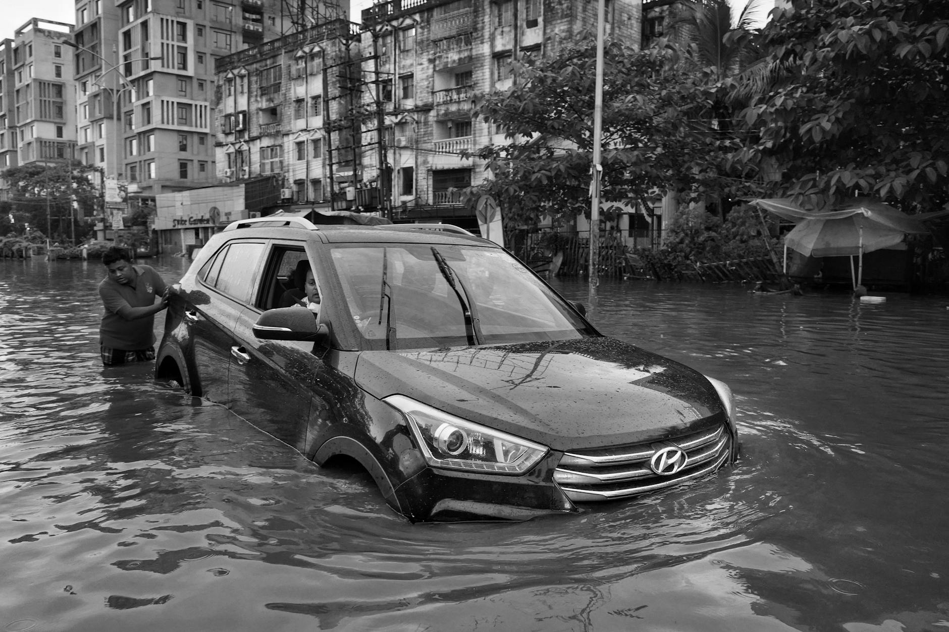man pushing car on street in water
