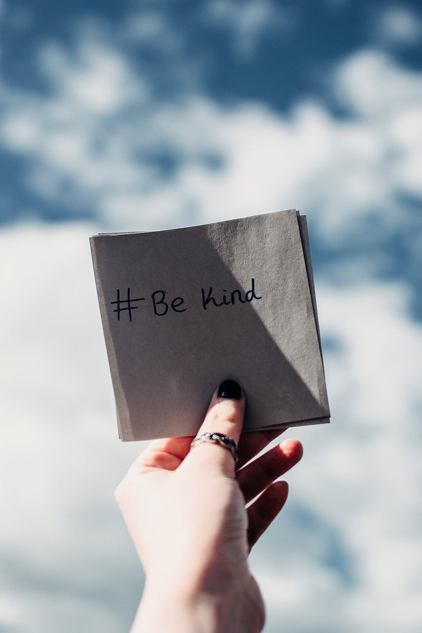 person holding note with be kind text